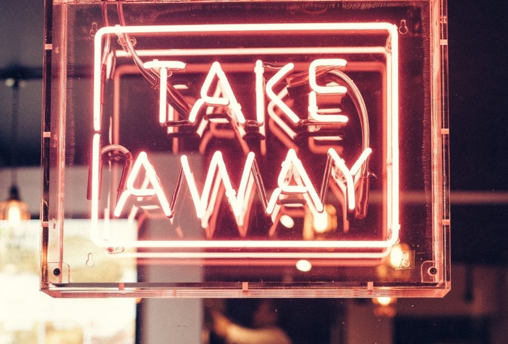 Imagen de un letrero de Take Away neón a la entrada de un restaurante.